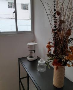 un tavolo con macchinetta del caffè e un vaso con fiori di Apartamento Hogareño a Jarabacoa