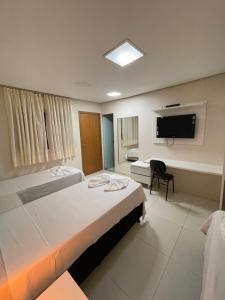 a hotel room with two beds and a television at Aldeia das Flores Hotel in Goiânia