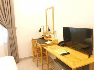 a room with a desk with a television and a table with a computer at La Paix Hue Riverside Villa in Hue