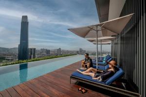 a group of people sitting on chairs on the edge of a swimming pool at Capri by Fraser, Bukit Bintang in Kuala Lumpur