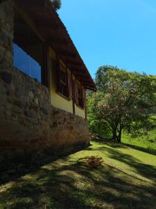 a stone building with windows and a tree at Chalé na Serra da Mantiqueira in Campos do Jordão