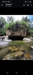 a picture of a river with rocks and trees at Pousada Camping dos Ypês in Guapimirim
