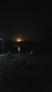 a person standing in a field at night at Pousada Camping dos Ypês in Guapimirim