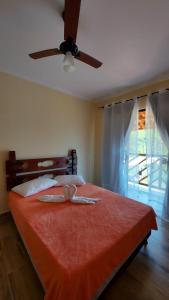 1 dormitorio con cama roja y ventilador de techo en Pousada Camping dos Ypês en Guapimirim