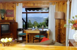 a living room with a table and a large window at Mount Joy Cottages in Knysna
