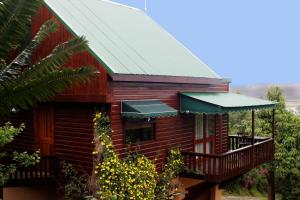 a red cabin with a balcony and a green roof at Mount Joy Cottages in Knysna