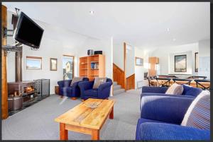 a living room with blue couches and a tv at Barcoo Chalet, alpine-getaways. in Dinner Plain