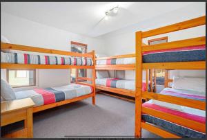 a room with three bunk beds in a house at Barcoo Chalet, alpine-getaways. in Dinner Plain