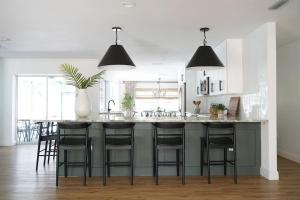 una cocina con una gran isla con taburetes negros en Remodeled 4BR Pool Home / Golf View/Near Beaches, en Sarasota