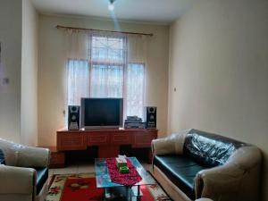 a living room with a couch and a television at Villa Bukit Asri No 12 Berastagi View in Berastagi