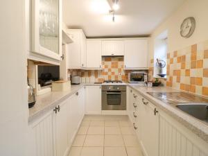 a kitchen with white cabinets and a sink at River Cottage in Burton Bradstock +12 photos