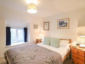 a bedroom with a large bed and a window at River Cottage in Burton Bradstock