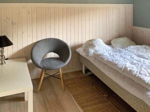 レズビュハウンにあるThree-Bedroom Holiday home in Rødby 14のベッドの横に椅子が備わるベッドルーム1室