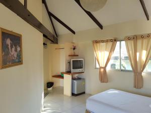 a bedroom with a bed and a tv and windows at Casa Holiday Hotel SHA in Phitsanulok