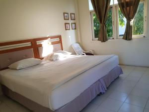 a bedroom with a large bed in a room with windows at Casa Holiday Hotel SHA in Phitsanulok