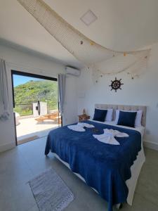 a bedroom with a bed with blue sheets and a large window at Casa Corazul in Arraial do Cabo