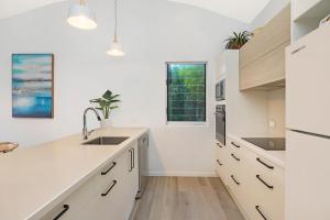 a kitchen with white counters and a sink and a window at Andari Holiday Apartments in Sunshine Beach