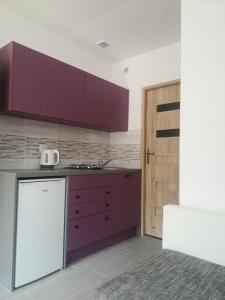 a kitchen with purple cabinets and a door at Agroturystyka Alex in Szczecinek