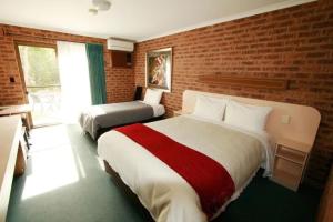 una camera d'albergo con due letti e un muro di mattoni di Eildon Parkview Motor Inn Room 11 a Eildon