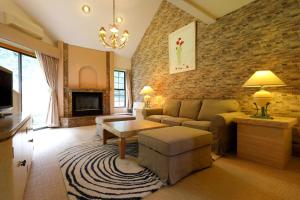 a living room with a couch and a brick wall at Hakuba Royal Suites in Hakuba