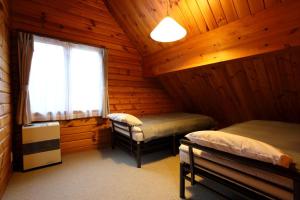 1 dormitorio con 2 camas en una cabaña de madera en Hakuba Happo Log Chalets, en Hakuba