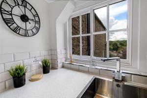 cocina con reloj en la pared y fregadero en Comfy Dales holiday base on Market Place of historic market town, en Richmond