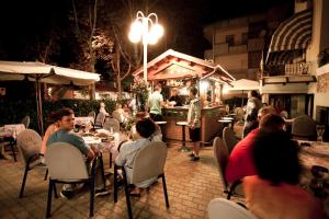 a group of people sitting at a restaurant at night at Hotel Dolcevita in Cesenatico
