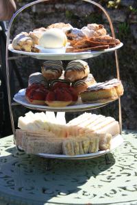 uma exibição em três níveis de produtos de pastelaria e sobremesas numa mesa em School House Cottage B&B and tea garden em Hawkshead