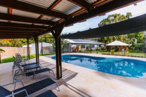 uma piscina com uma pérgola e cadeiras em redor em Kooyong Apartment 1 em Arcadia