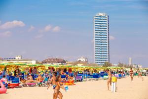 un gruppo di persone su una spiaggia con ombrelloni di Hotel Dolcevita a Cesenatico