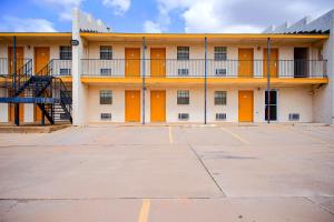 ein leerer Parkplatz vor einem Gebäude mit orangefarbenen Türen in der Unterkunft Duncan Inn by OYO, OK - Hwy 81 Near Chisholm Casino in Duncan