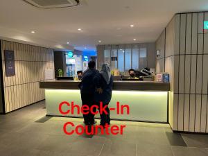 a couple standing at the counter of a check in counter at Ceylonz Suites Kuala Lumpur, Roam in Kuala Lumpur
