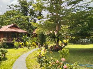 a garden with a tree and a house at Khao Sok River & Jungle Resort in Khao Sok National Park