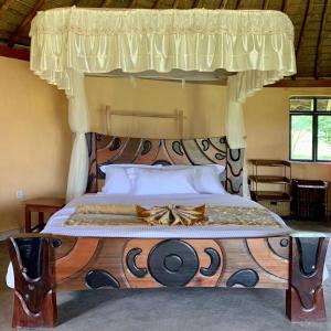 a bedroom with a wooden bed with a canopy at Jacaranda Bush Camp in Musiara Campsite