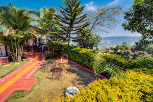 ein Garten mit Tischen und Stühlen und Palmen in der Unterkunft Lifeline Villas - Marvel Valley View 5Bhk With Private Pool,Surrounded by strawberry farms in Mahabaleshwar