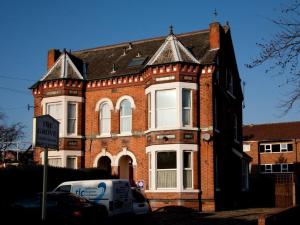 a large brick building with a van parked in front of it at Grove Guest House in Nottingham