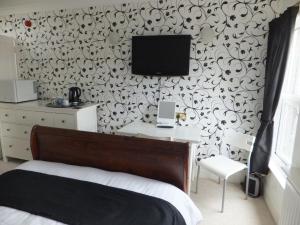 a bedroom with a bed and a tv on a wall at Grove Guest House in Nottingham