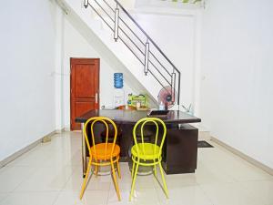 a kitchen with two chairs and a table and stairs at OYO Life 90587 Domen Homestay Syariah in Krui