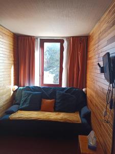 a living room with a blue couch in front of a window at Studio transformé en 2 pièces avec cloison amovible sur La Plagne Bellecôte in Sangot +33 photos