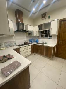 a kitchen with white counters and wooden cabinets at Luxury Guest House in Bahria Town in Rawalpindi