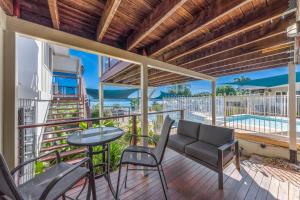 balcón con mesa, sillas y piscina en Airlie Apartments, en Airlie Beach