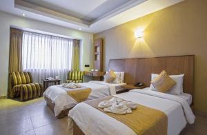 a hotel room with two beds with towels on them at THE CASTELLO RESIDENCY in Coimbatore