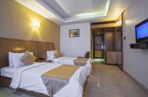 a hotel room with two beds and a flat screen tv at THE CASTELLO RESIDENCY in Coimbatore