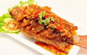 a piece of fish on a plate with vegetables at Sweet Time Bungalows in Koh Rong Sanloem