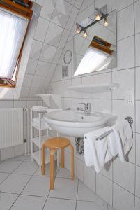 a white bathroom with a sink and a stool at Ferienwohnungen im Huus Janssand in Bensersiel