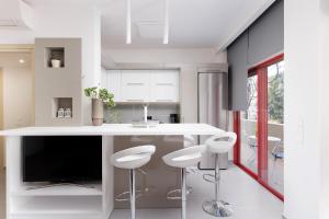 a kitchen with a white island with stools and a tv at A Luxury Retreat in Corfu Town by Konnect in Corfu