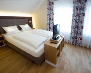 a bedroom with a bed and a table with a television at Genießerhotel Limbacher in Herrieden