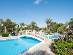 a bridge over a pool at a resort with palm trees at Nelia Sea Breeze in Ayia Napa
