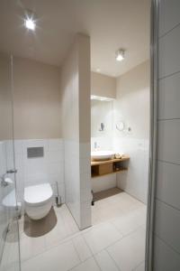 biała łazienka z toaletą i umywalką w obiekcie Genießerhotel Limbacher w mieście Herrieden
