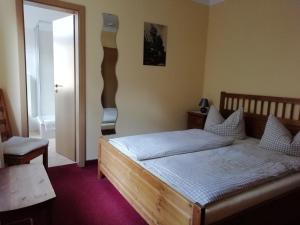 a bedroom with a wooden bed and a chair at Gaststätte & Pension Zum Türmer in Annaberg-Buchholz